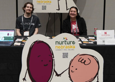 Lily Dohmen and Kavanaugh Splittgerber sit at Nurture Nebraska booth.
